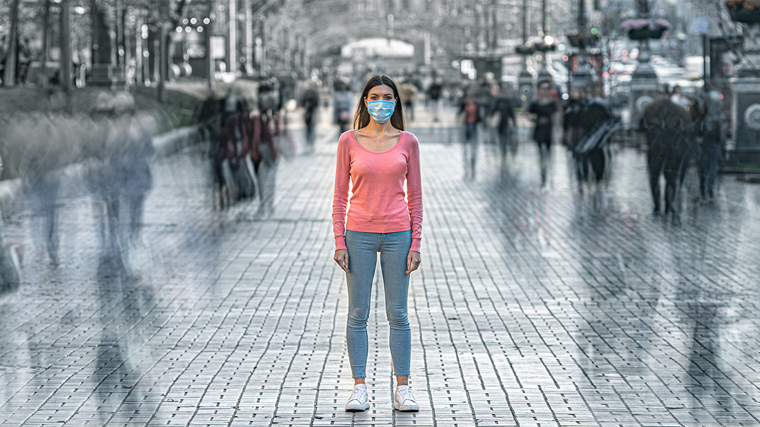 Woman standing in street wearing a mask